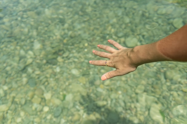 Une main féminine se déplaçant dans l'eau turquoise d'une piscine naturelle