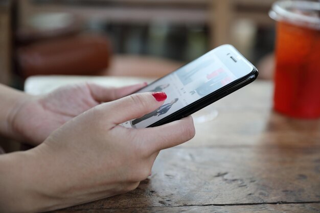 Main féminine avec stock de trading smartphone en ligne dans un café en plein air, concept d'entreprise