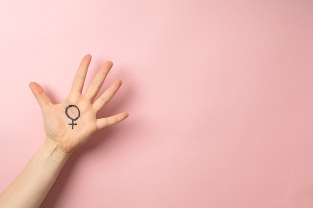 Main féminine avec symbole féminin de Vénus sur fond rose pour la journée internationale de la femme