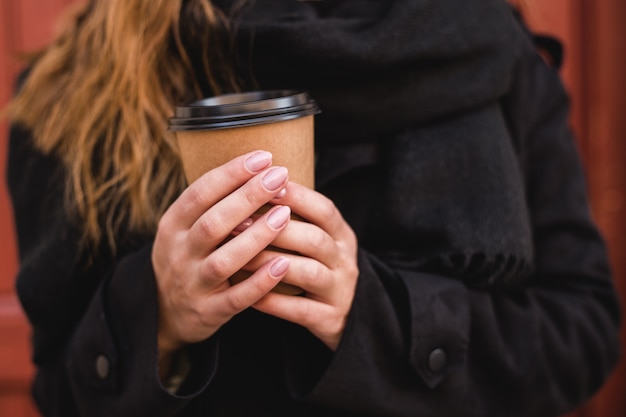 Main féminine avec une tasse de café à emporter