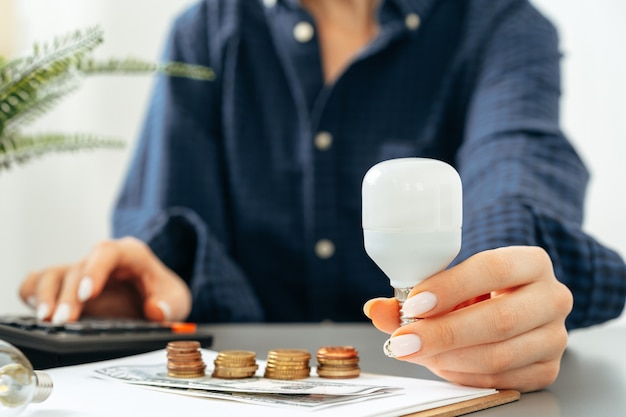 Main féminine tenant une ampoule au-dessus de la table