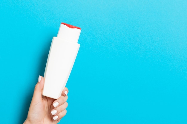 Main féminine tenant une bouteille de cosmétiques