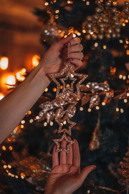 Main féminine tenant des étoiles de Noël dorées sur fond de lumières bokeh dorées festives