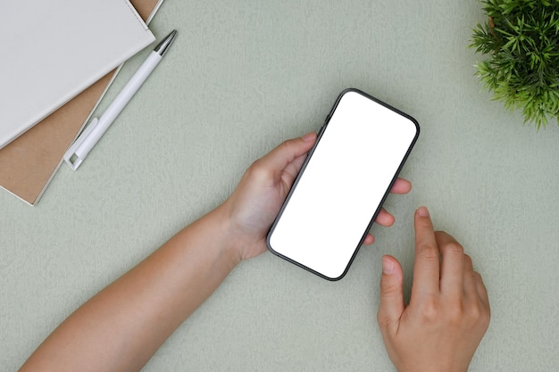 Une main féminine tenant une maquette de smartphone sur son bureau moderne et minimal