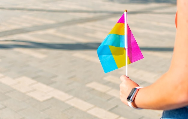 Main féminine tenant un petit drapeau sexuel pan lgbt Drapeau de fierté LGBT