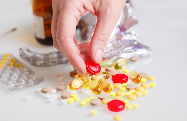Main féminine tenant des pilules à la main. Femme tenant des pilules à la main sur fond de comprimés et de gélules colorés