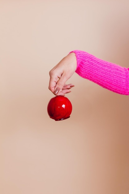 Une main féminine tenant une pomme d'amour.