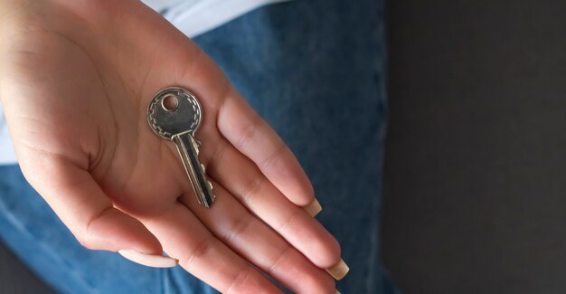 Main féminine tenant un porte-clés en forme de maison.