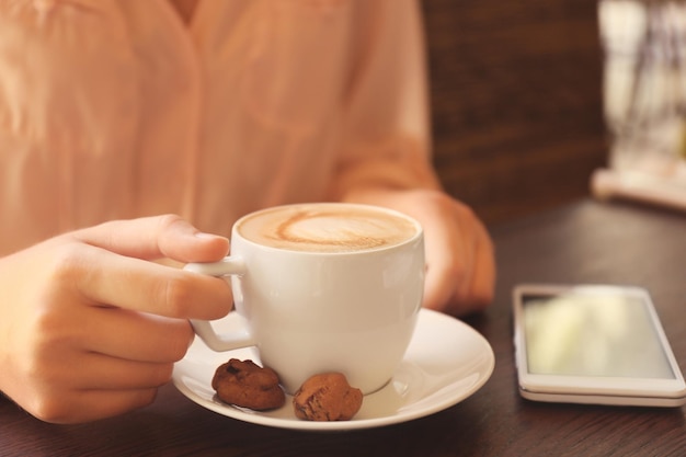 Main féminine tenant une tasse de café au café