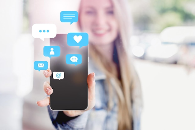 main féminine tenant et utilisant un média social sur un téléphone mobile avec des icônes de notification telles qu'un commentaire de message et une étoile au-dessus de l'écran du smartphone