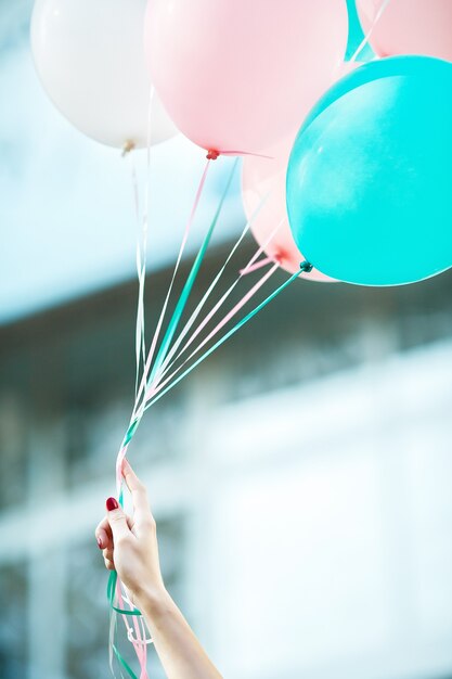 La main féminine tient des ballons en latex multicolores volants