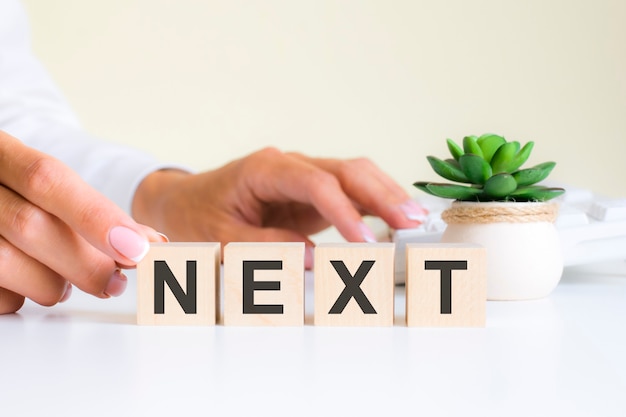 La main féminine tient un bloc avec la lettre N du mot suivant. le mot est situé sur une table de bureau blanche sur le fond d'un clavier blanc. concepts financiers, marketing et commerciaux