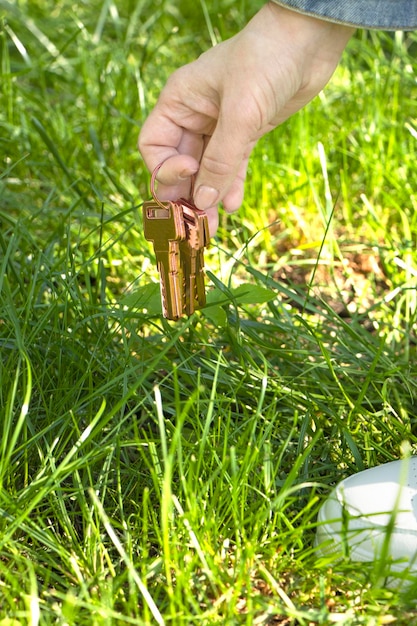la main féminine tient les clés Un trousseau de clés trouvés dans l'herbe Le concept de clés perdues