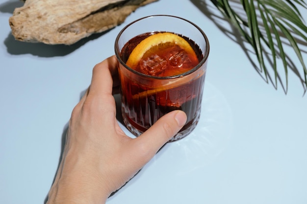 Une main féminine tient un cocktail de mezcal negroni