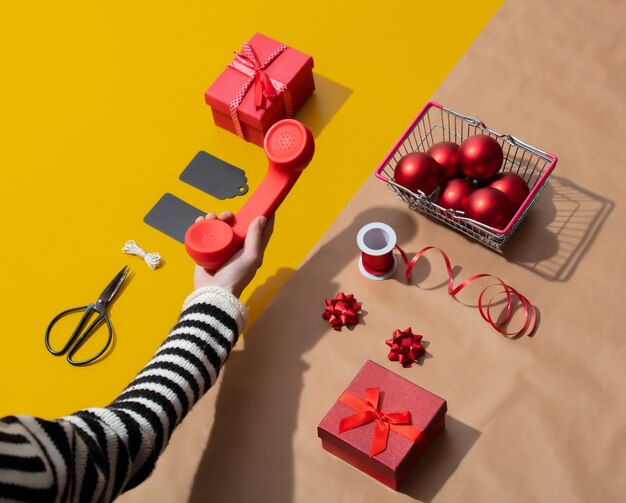 Main féminine tient un combiné rouge près des objets de Noël