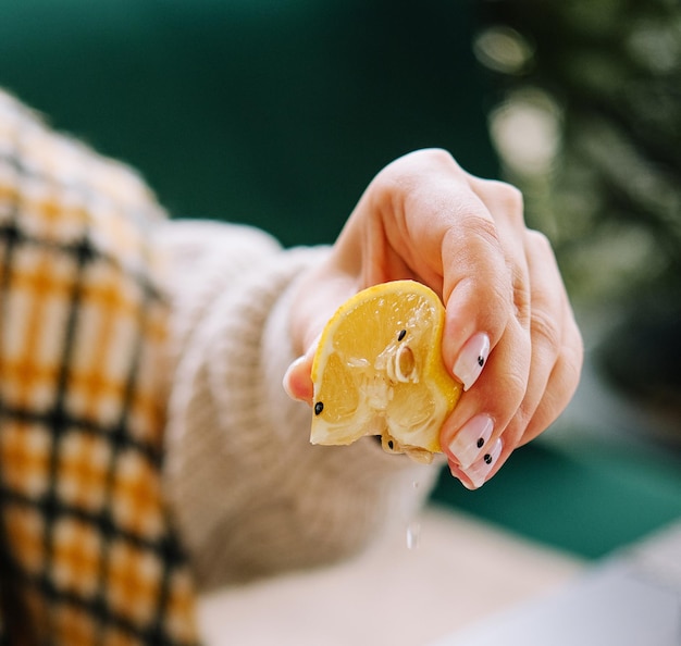 La main féminine tient un demi-citron jaune et serre