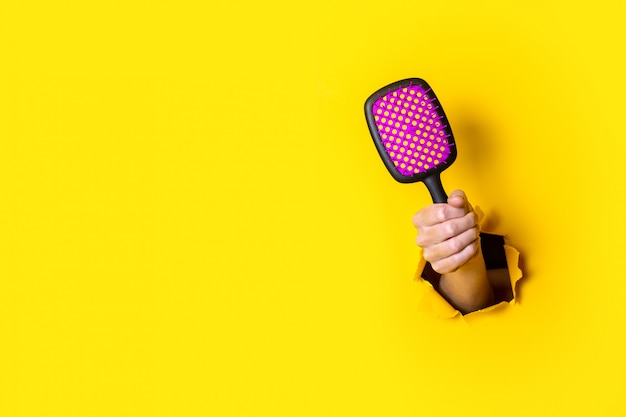 Main féminine tient un grand noir avec une brosse à cheveux rose