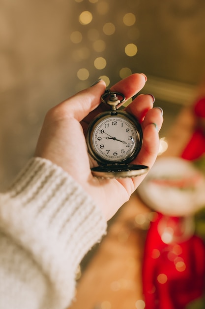 Main féminine tient l'horloge sur la surface des lumières floues