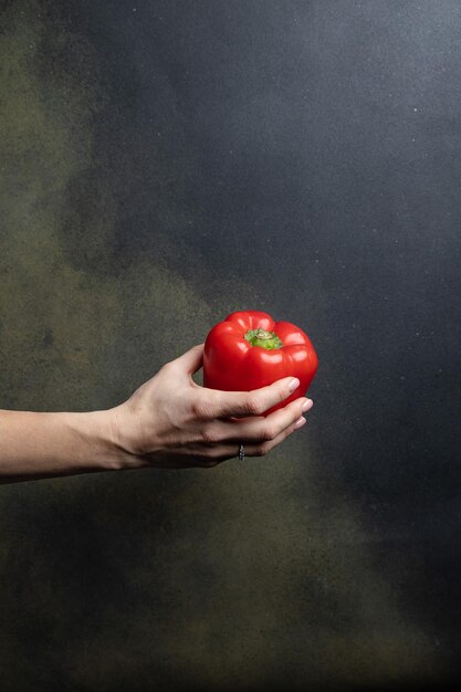 la main féminine tient des légumes sur un fond sombre