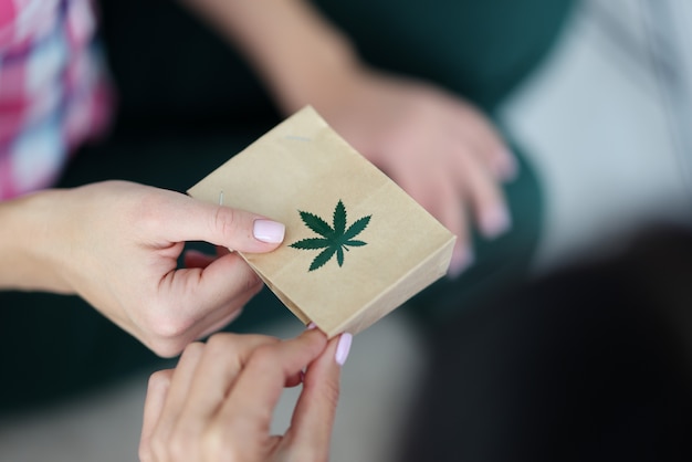 Main féminine tient un sac en papier avec une image du symbole de la marijuana