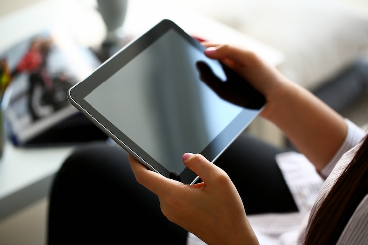 Photo main féminine tient la tablette dans le cadre de la maison tandis que