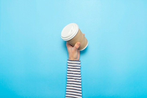 Main féminine tient une tasse de papier avec du café