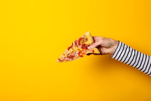 Main féminine avec une tranche de pizza chaude fraîche