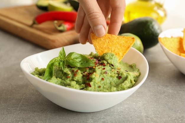 La main féminine trempe la tranche de chips dans le guacamole, Close up