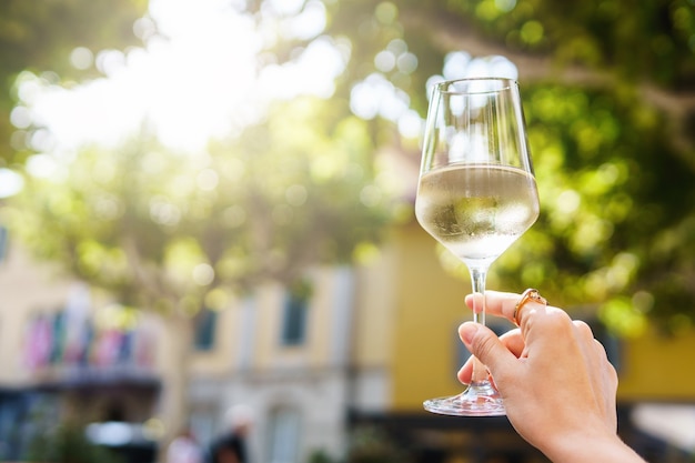 Main féminine avec un verre de vin blanc