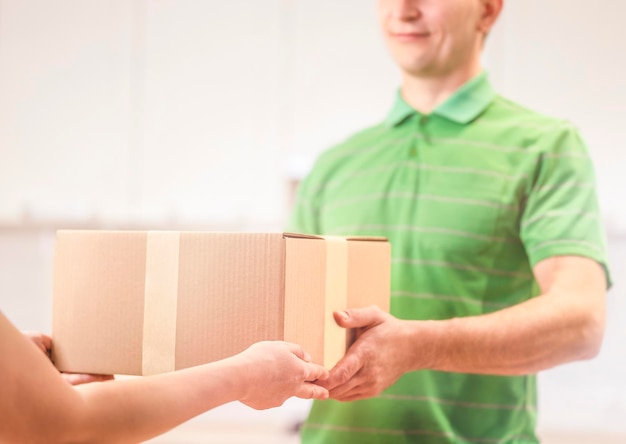 Main de femme acceptant une boîte de livraison d'un livreur caucasien professionnel à la maison.