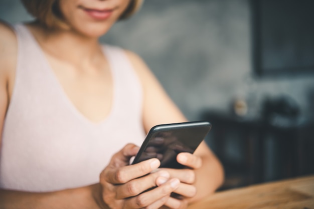 Main de femme d'affaires asiatique utilisant et touchant un téléphone intelligent avec un écran vide blanc blanc.