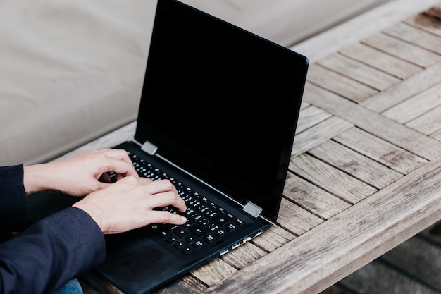 Main de femme d'affaires asiatiques tapant sur un ordinateur portable sur la table en bois, concept de démarrage de travail de vacances.