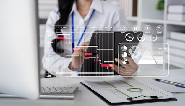 Main de femme d'affaires Chef de projet travaillant et mettant à jour les tâches et diagramme de Gantt planifiant un diagramme virtuel avec une tablette et un ordinateur portable au bureau