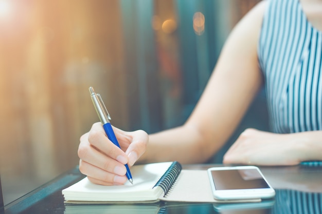 Main de femme d&#39;affaires écrit sur un cahier