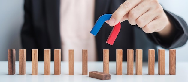 Main de femme d'affaires tenant l'aimant et tirant l'homme figure en bois du bloc de foule