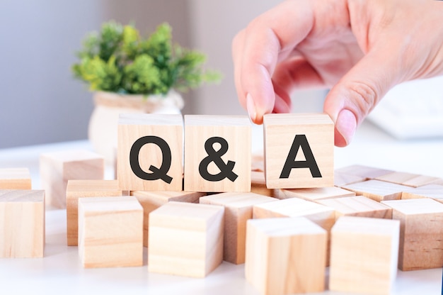 Photo main de femme d'affaires tenant q et un mot avec un bloc de cube en bois. réponse, question ask, information, concepts de communication