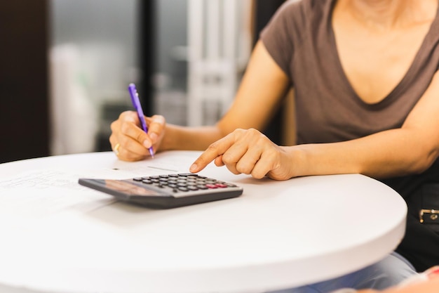 Main de femme d'affaires tenant un stylo travaillant sur une calculatrice pour calculer les données de l'entreprise