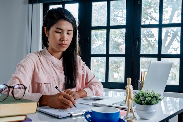 Main de femme d&#39;affaires travaillant avec des données financières et une calculatrice sur le bureau blanc