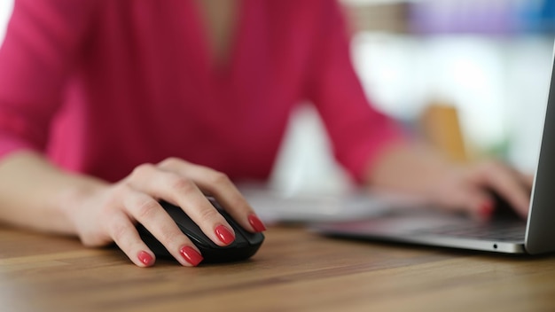 Main de femme d'affaires travaillant à l'ordinateur à l'aide de gros plan de souris