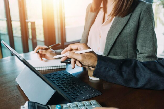 Main de femme d'affaires travaillant avec une tablette d'ordinateur portable et un téléphone intelligent dans un bureau moderne avec un diagramme d'icône virtuelle au bureau moderne à la lumière du matin