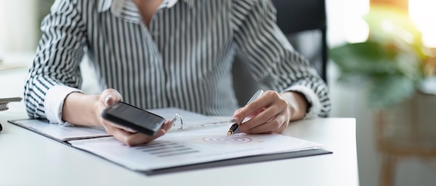 Main de femme d'affaires travaillant avec un téléphone mobile et un concept financier cible d'objectif de stratégie d'entreprise