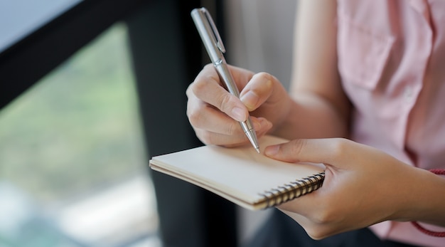 main de femme à l&#39;aide d&#39;un crayon et d&#39;écrire sur un cahier