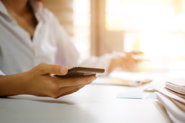 Main de femme à l&#39;aide de smartphone mobile sur la table de bureau.