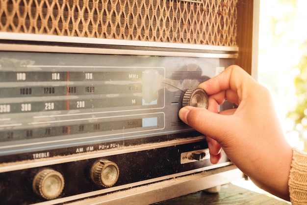 Main de femme ajustant le récepteur radio vintage bouton