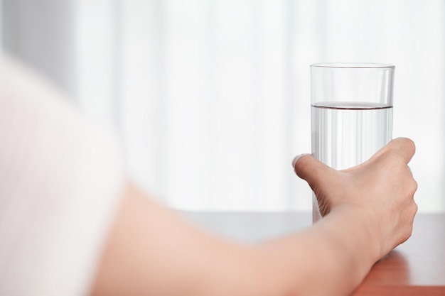 Main de femme asiatique tenant un verre d'eau potable