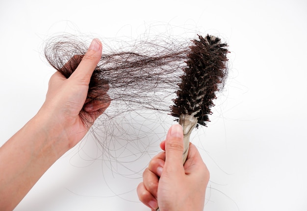 Une main de femme attrape les cheveux manquants sur le pinceau isolé sur fond blanc