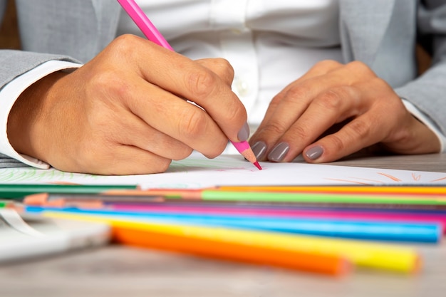 La main de la femme au bureau dessine avec des crayons sur papier