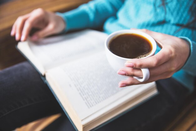 Main de femme café avec livre