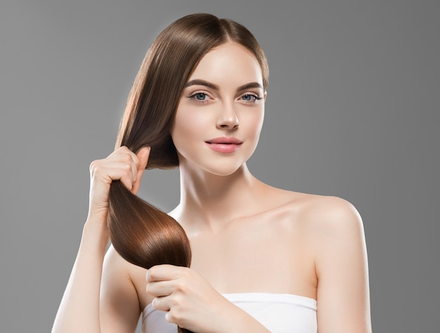 Main de femme de cheveux longs touchant le modèle de coiffure brune lisse de cheveux