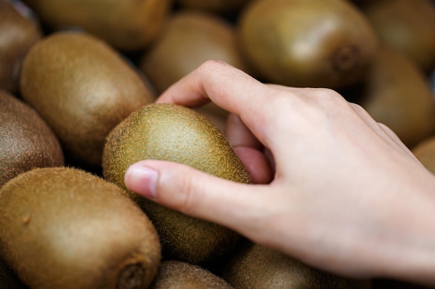 Main de femme choisissant des kiwis au supermarché